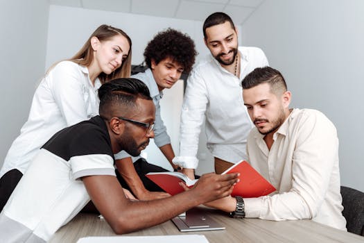 A group of diverse colleagues collaborating in an office setting, engaging with a document together.