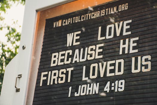 Church sign displaying biblical verse about love from 1 John 4:19 in outdoor setting.