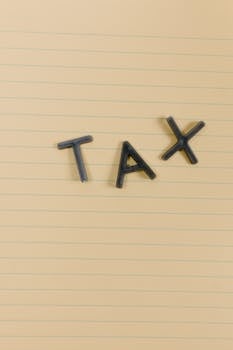 Conceptual still life image with the word 'Tax' on lined paper, perfect for financial themes.