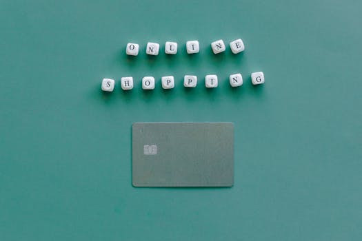 Flat lay of credit card and 'Online Shopping' text on green background, symbolizing ecommerce.